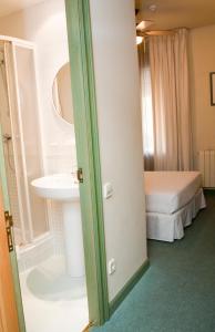 a bathroom with a sink and a bed in a room at Hostal Navarra in Pamplona