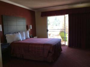 a hotel room with a bed and a large window at Americas Best Value Presidents Inn on Munras in Monterey