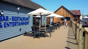 ein Restaurant mit Tischen, Stühlen und Sonnenschirmen in der Unterkunft Country Coastal Holidays - Families and Couples only in New Romney