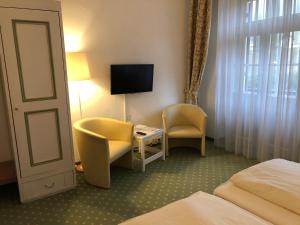 ein Hotelzimmer mit einem Bett, einem Stuhl und einem TV in der Unterkunft Hotel zur Post in Kreuth