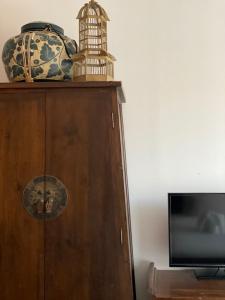 a wooden cabinet with a bird cage and a television at See You Soon, Chiang Mai in Chiang Mai