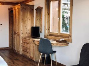 Habitación con escritorio, TV y silla. en Hôtel Chalet Royal, en Veysonnaz