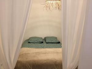 Cette chambre comprend un lit avec deux oreillers et des rideaux. dans l'établissement ★★★ Paradis Prado Mermoz proximité Mer★★★, à Marseille