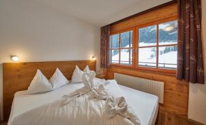 een slaapkamer met een bed met witte lakens en een raam bij Chalet Lodge Hubertus in Saalbach Hinterglemm