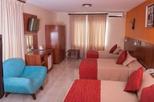 una habitación de hotel con 2 camas y una silla azul en Hotel Mitru - Tarija, en Tarija