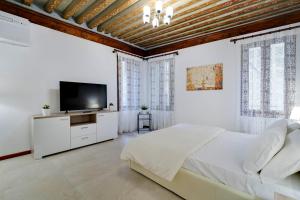 - une chambre blanche avec un lit et une télévision à écran plat dans l'établissement Ca' Rialto, à Venise