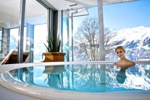 a woman in a swimming pool with mountains in the background at Hotel Silberhorn - Residences & Spa Wengen in Wengen