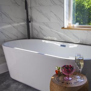 a bath tub with a bowl of fruit and a glass of wine at Crumplebury in Whitbourne