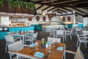 Un restaurante con mesas y sillas y una cocina. en El Beso Adults Only at Ocean Coral & Turquesa All Inclusive, en Puerto Morelos