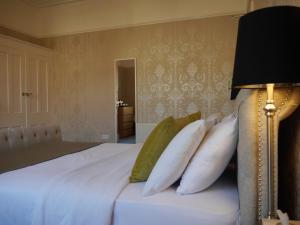 una camera da letto con un letto con lenzuola bianche e cuscini verdi di Haversham House - Adults Only a Llandudno