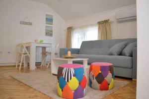 a living room with a couch and two colorful stools at Apartman Iva in Belgrade