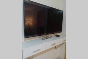 TV de pantalla plana en la parte superior de una cómoda blanca en 2BR Apartment - Pasig Stay, en Manila