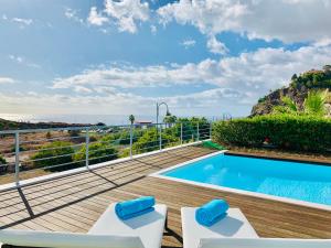 a deck with a swimming pool and two lounge chairs at Villa Mar Garajau in Caniço