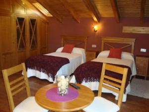 a room with two beds and a table and chairs at Apartamentos Rurales Posada de las Hoces in Bustiello de Paredes