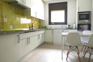 a kitchen with white cabinets and a table and chairs at ALOJAMIENTO CON JARDIN 20KM BARCELONA in Vilassar de Dalt