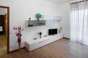 een witte woonkamer met een tv aan een witte muur bij Casa Primavera in Bergamo