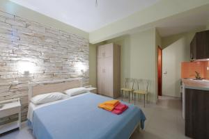 a bedroom with a bed and a stone wall at Holiday Rooms in Otzias