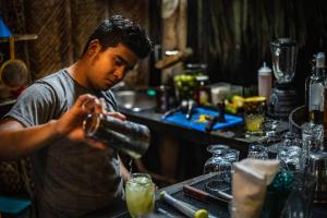 Ein Mann steht hinter einer Bar und macht einen Drink. in der Unterkunft Senda Cabaña Barlovento in Los Naranjos