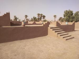 a building with steps and palm trees in the desert at jardin du desert in Mhamid