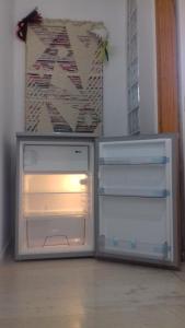 an empty refrigerator with its door open in a room at Vitina's little house in Vytina