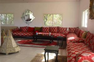 a living room with a red couch and a table at Villa Green flower in Casablanca