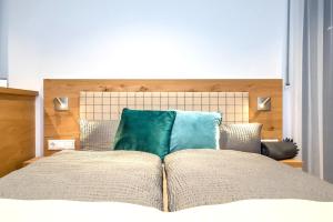 a bed with two blue pillows on top of it at REINERS Quartier - relaxed living in Bruckberg
