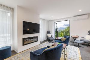 a living room with a fireplace and blue chairs at MyHolidays - The Four Seasons Queenstown in Queenstown