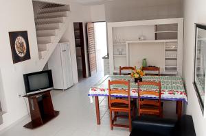 a dining room with a table and chairs and a television at Apartamentos Porto Cal in Barra de São Miguel