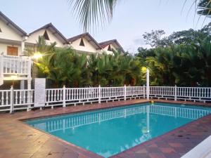 a swimming pool in front of a house with a white fence at Hotel Campestre La Toscana in Villavicencio