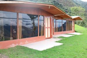 a house with glass doors on a grassy hill at Llactapata Lodge overlooking Machu Picchu - camping - restaurant in Salcantay