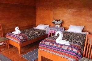 Dos camas en una habitación con cisnes. en Llactapata Lodge overlooking Machu Picchu - camping - restaurant, en Salcantay