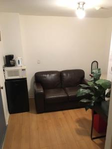 a brown leather couch in a living room with a microwave at Hotel Mini Inc in Montréal