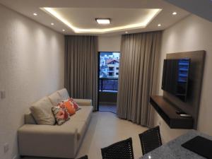 sala de estar con sofá y TV de pantalla plana en Apartamento em Bombinhas, en Bombinhas