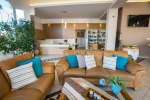 sala de estar con sofá marrón y almohadas azules en Helios Apartments, en Kato Daratso