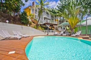 a swimming pool with chairs and a building at Cannelle in Deshaies