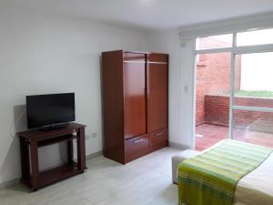1 dormitorio con 1 cama y TV en una mesa en MONOAMBIENTE CON COCHERA Y PATIO en Rosario