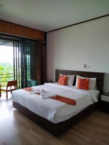 1 dormitorio con 1 cama blanca grande con almohadas de color naranja en Phumok Village Khao Kho en Khao Kho