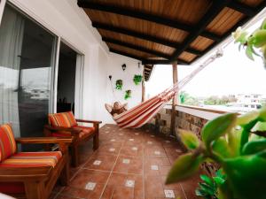 a room with a hammock and chairs on a balcony at Hotel Cucuve in Puerto Ayora
