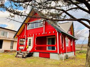 una casa roja con techo de gambrel en Tomy's Log House - Need CAR, en Shiraoi