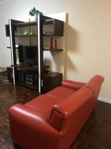 een rode leren bank in een woonkamer met een tv bij Apartamento Frente Mar in Balneário Camboriú