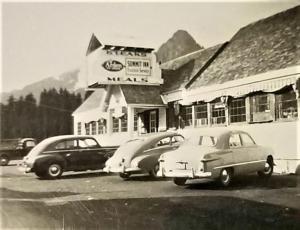 dos coches viejos estacionados frente a un motel en The Summit Inn, en Snoqualmie Pass