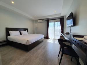 een slaapkamer met een bed en een bureau met een televisie bij T-NEE Hotel@Udon in Udon Thani
