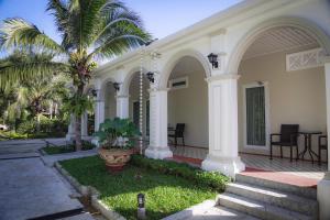 a white house with palm trees and a courtyard at Maikhao Home Garden Bungalow in Mai Khao Beach