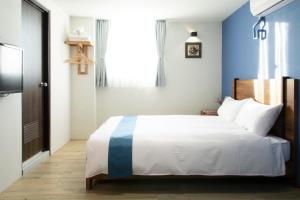 a bedroom with a bed with a blue and white blanket at Mulan Light Inn in Tainan