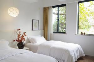 2 camas en una habitación blanca con ventana en Xiamen Gulangyu Heitan Hotel en Xiamen