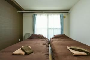 two beds in a small room with a window at 札幌市中心部大通公園まで徒歩八分観光移動に便利なロケーションe608 in Sapporo