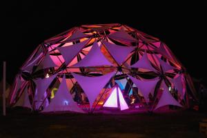 una grande tenda è illuminata con luci viola di Woodstock Jungle Camp a Cat Ba