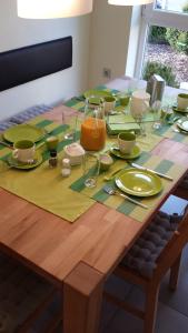a wooden table with green plates and glasses on it at Pension Wauri , Gästezimmer in Waldenbuch