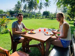 a man and woman sitting at a table eating food at Crown Holiday Village near Marawila in Nattandiya