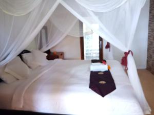 a bedroom with a white bed with a white canopy at Ritinula Resort in Tejakula